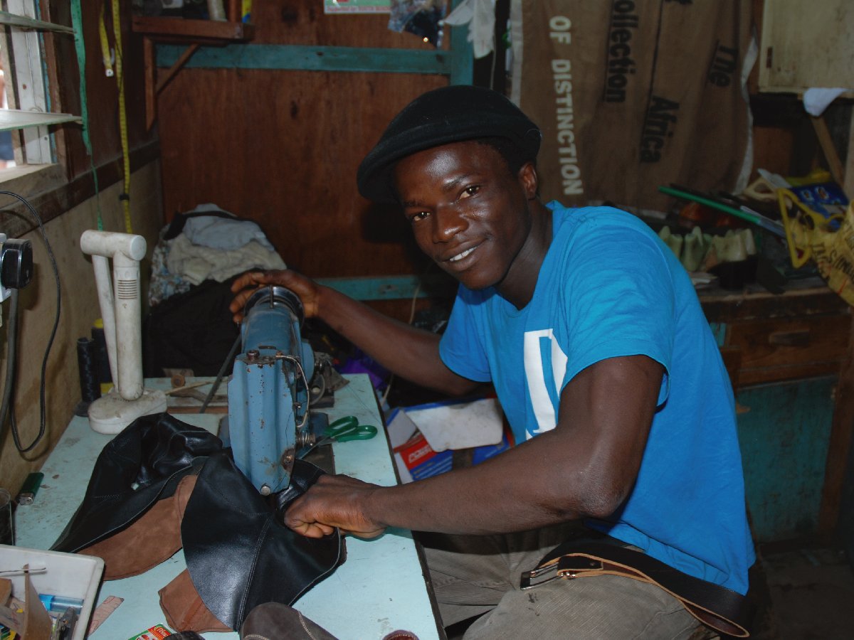 Young entrepreneur supported by FATE Foundation smiling as he works at his sewing machine