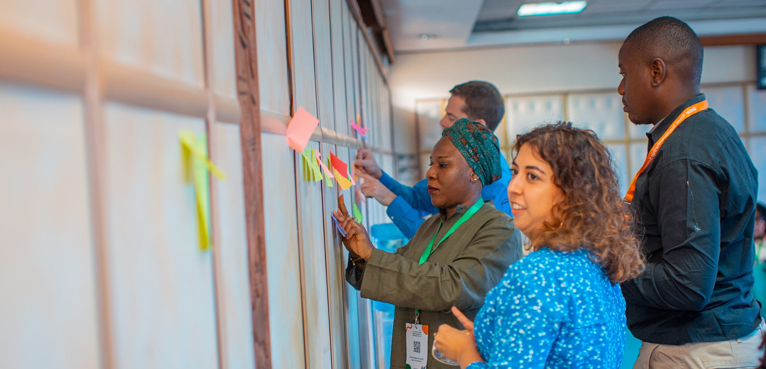 YBI Members, staff and young entrepreneurs adding sticky notes to a board at a training session